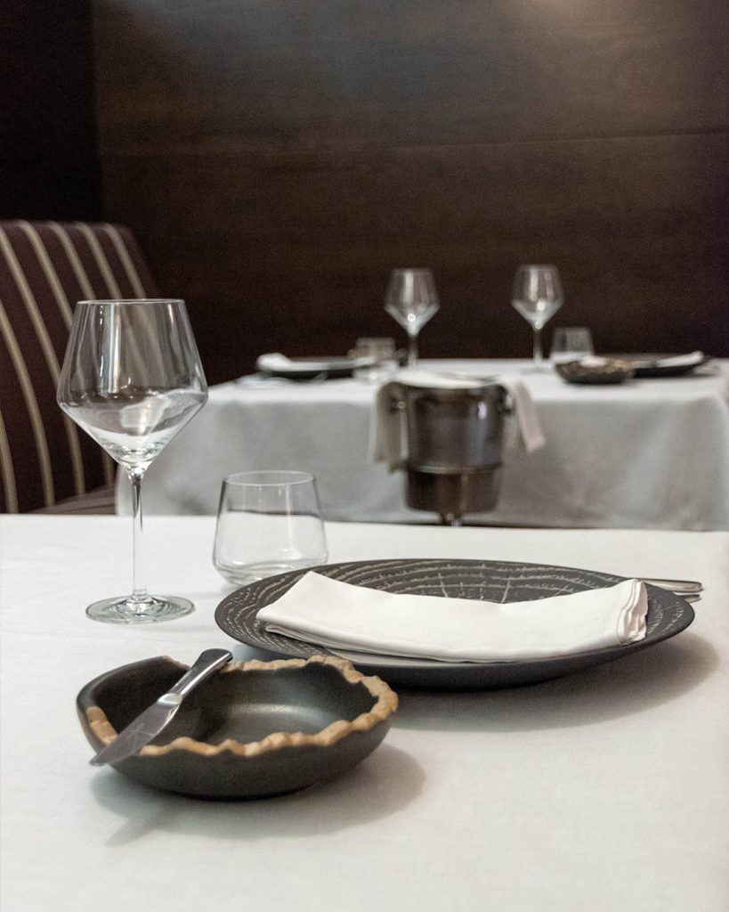 Mesa de restaurante vestida con copas de vino, vajilla y cubertería